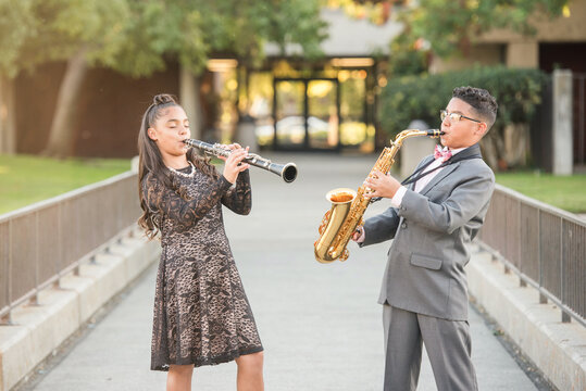 Twins playing their instraments together outside
