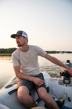 Man motoring through harbor at sunset in inflatable dinghy