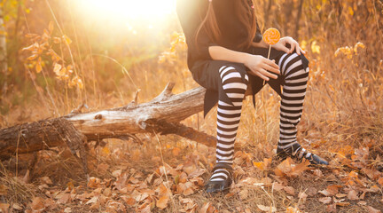Halloween kids going to collect candy. Trick-or-treating. сhild in carnival costume witch outdoors. Celebrate halloween. Unrecognizable girl in autumn forest smiling and holding of sweets candy