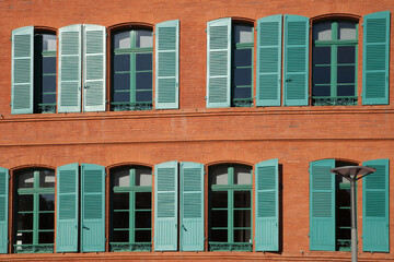 Fototapeta premium Façade de briques aux volets verts dans la ville de Montauban