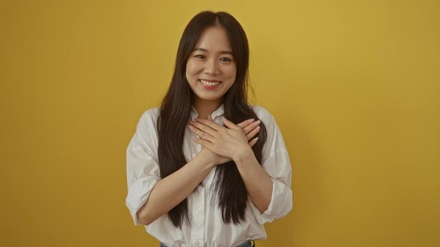 Smiling woman posing cheerfully against a vibrant yellow wall looking grateful