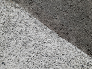 Close-up shot of a textured concrete surface showcasing the contrast between two different shades of rough cement.