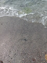 Portrait of waves, sand and small rocks on the beach