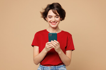 Young smiling happy cheerful woman she wear red t-shirt casual clothes hold in hand use mobile cell...