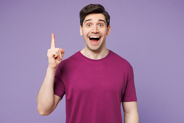 Young insighted smart proactive man wear violet t-shirt casual clothes holding index finger up with...