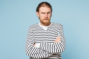 Young sad grumpy unhappy man he wearing striped sweatshirt casual clothes hold hands crossed folded look camera isolated on plain pastel light blue cyan background studio portrait. Lifestyle concept.