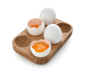 Cracked and whole chicken eggs in wooden holder isolated on white background