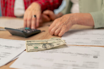 close-up in bright kitchen hands with American bills calculator payment receipts calculator hard pension utilities