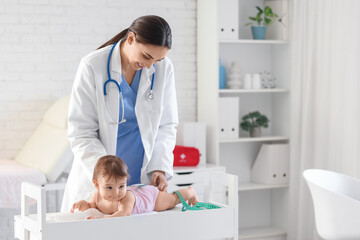 Female pediatrician measuring little baby on table in clinic