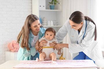 Female pediatrician with little baby and mother in clinic