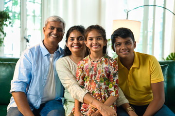Cheerful Indian Asian family poses for a close-up photo while sitting on the sofa