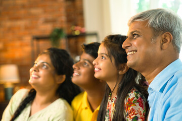 Cheerful Indian Asian family poses for a close-up photo while sitting on the sofa