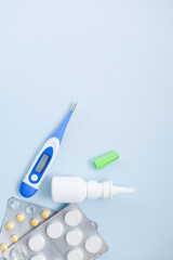 Seasonal diseases. Cold, runny nose, cough Medicines, spray and syrup, thermometer, pills, capsules on pastel background