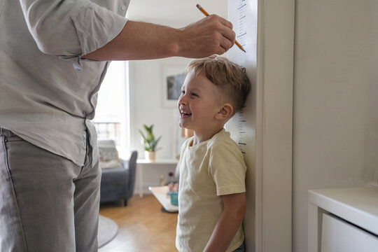 Father placed his son near the door frame and measured his height.