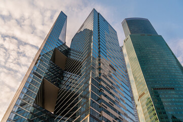 Fototapeta premium Angled view of modern skyscrapers in business district against blue sky. Looking Up high-rise office buildings.