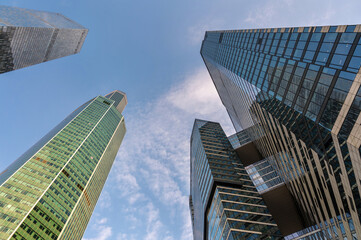 Naklejka premium Angled view of modern skyscrapers in business district against blue sky. Looking Up high-rise office buildings.