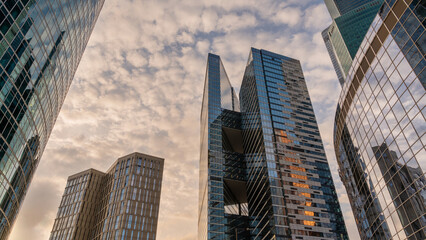 Obraz premium Angled view of modern skyscrapers in business district against blue sky. Looking Up high-rise office buildings.