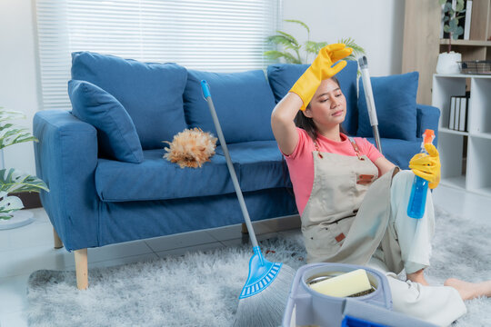 Tired woman takes a break from cleaning her living room, surrounded by tools and products, dedicated to keeping her apartment spotless - Powered by Adobe