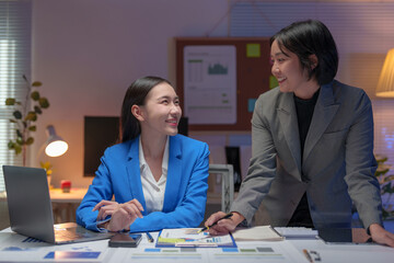 Two happy Asian businesswomen Discuss financial document work starting a business Creative team brainstorming meeting, business partnership or teamwork concept of office colleagues.
