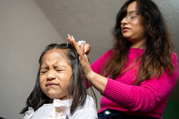 Fototapeta premium Mexican girl angry while her mother combs her hair
