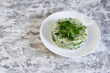 Vegan, vegetarian delicious dish. Rice with spinach on a white plate on a light background with copy space