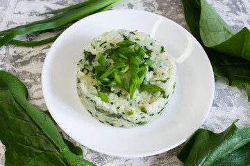 Vegan, vegetarian delicious dish. Rice with spinach on a white plate and fresh spinach leaves on the table, flatlay. Concept of healthy eating