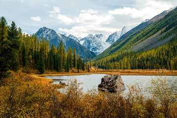 Shavlinskoye lake in Altai during the golden autumn, against the background of snow-capped mountains UNESCO heritage