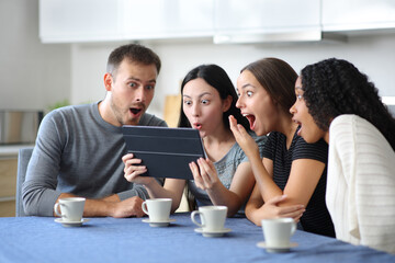 Fototapeta premium Amazed interracial friends cheking tablet in the kitchen
