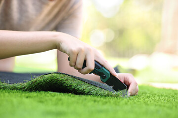 Woman hand cutting and installing artificial grass