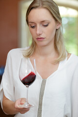 beautiful woman tasting wine while sitting in restaurant