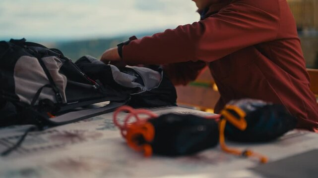 Man packing hiking gear on a table outdoors, preparing for an adventure. Concept of outdoor activities, hiking, adventure, preparation for outdoor exploration