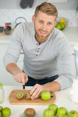 happy man cut with a knife a kiwi fruit