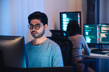 Asian software developers working on multiple screens displaying code and application diagrams at...