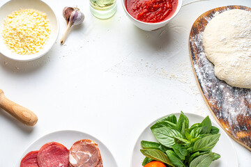 Ingredients for making Italian pizza: dough, tomato sauce, parmesan, tomatoes, basil, garlic, sausage on a white table. Real pizza recipe. Copyspace