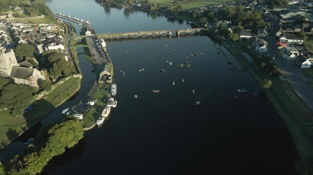 Killaloe town with boats gathering for a fishing competition on a calm river in ireland, aerial view