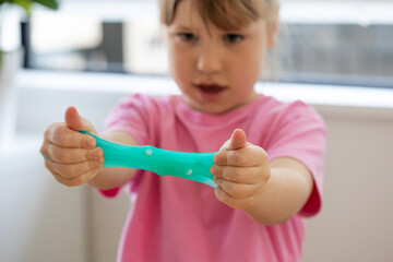 A child playing with bright, blue slime, enjoying a fun and creative indoor activity.