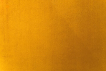 Gold or orange paint on cement wall texture as background.