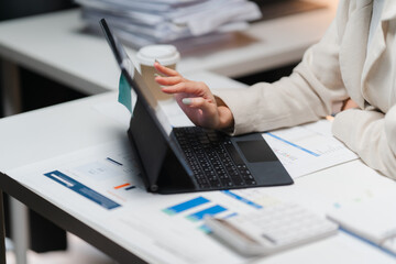 Strategic Planning: A businesswoman analyzes financial data on her laptop, surrounded by reports and a calculator.  The image conveys focus, precision.