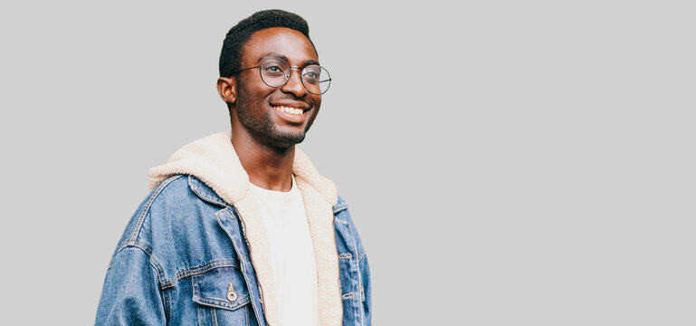 Portrait happy modern smiling young african man in glasses looking away isolated on gray background
