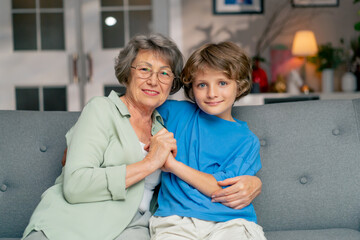Fototapeta premium a bright living room with sofa grandmother sitting with grandson on sofa hugging looking at camera happy family
