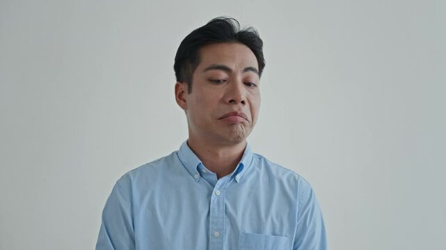Medium close up of arrogant Asian man looking down upon isolated on white background, copy space