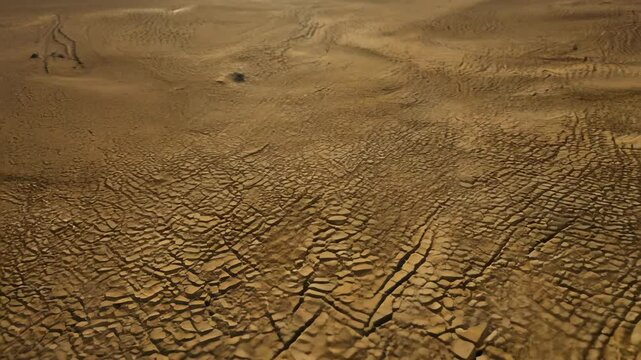 Drought impacts visible in cracked earth as water levels drop in an arid desert landscape during the summer months