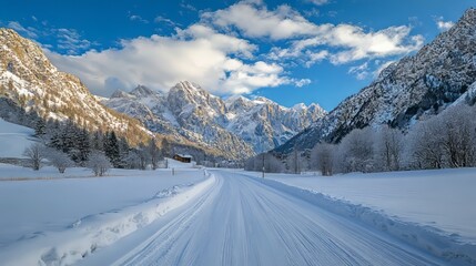 Scenic snow-covered road winding through the alpine mountains in winter, featuring pristine white snow, majestic pine trees, and clear blue sky, capturing the serene beauty of a winter landscape in th