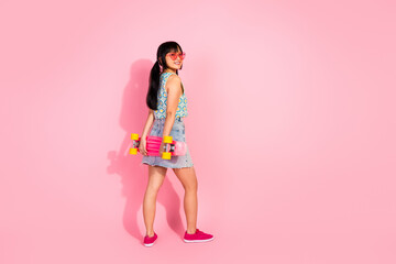 Photo of cheerful optimistic girl wear stylish clothes hold penny board isolated on pink color background