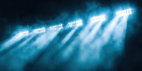 A close-up of stadium floodlights brightens the field. Strong beams of light cut through the darkness, generating a feeling of energy and excitement.