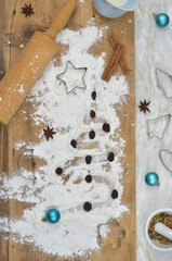 Christmas cookies preparations, Christmas tree drawn with flour on a wooden background. Top view.