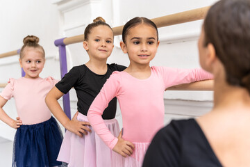 Woman with little ballerinas in cute skirt during ballet training in studio