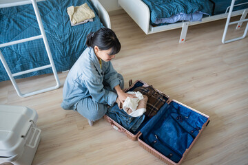 Asian girl preparing vacation in bedroom. Woman doing checklist before holidays trip in university...