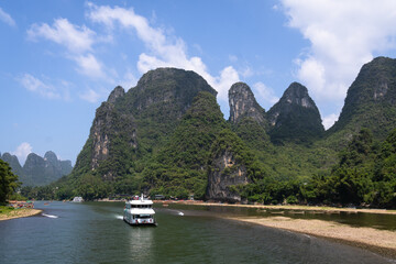 Guilin, China: A cruise ship sails along the famous karst landscape of the Li river between Guilin and Yangshuo on a sunny day.