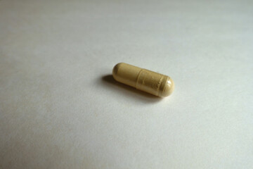 Closeup of one beige capsule of Saccharomyces boulardii probiotic dietary supplement